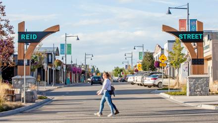 People walking across Reid Street by the gateway sign