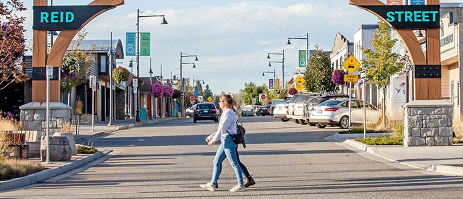 People walking across Reid Street by the gateway sign