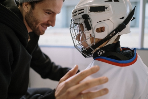 Man helping boy with hockey helmet