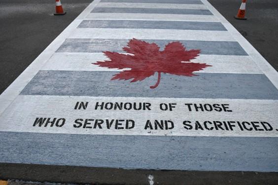 Newly painted crosswalk with the words in honour of those who served and sacrificed.